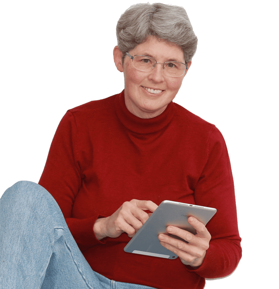 Claudia Barfuss, sitzend mit angezogenem Knie in einem dunkelroten Pullover. In der Hand ein Tablet. Sie lächelt.