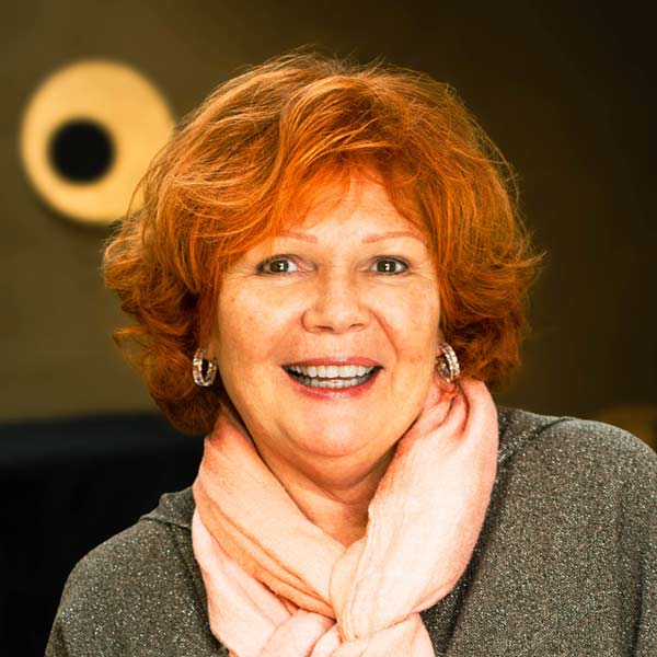 Portrait einer Frau mit rötlichen Haaren und einem rosa Schal.