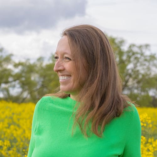 Denise Fritsch eine Frau mit schulterlangen blonden Haaren ist im Profil zu sehen. Im Hintgrund ein Rapsfeld und Bäume.