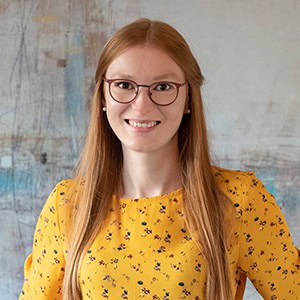 Portrait von Natalie Schilling in gelbem Oberteil mit Punkten. Sie lächelt direkt in die Kamera.