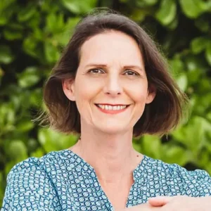 Sabina Dörring schaut in die Kamera und lächelst. Sie hat eine blaue Bluse mit weissen Tupfen an.