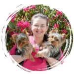 Porträt von Stéfanie Renou in jedem Arm je einen Yorkshire-Terrier hält.